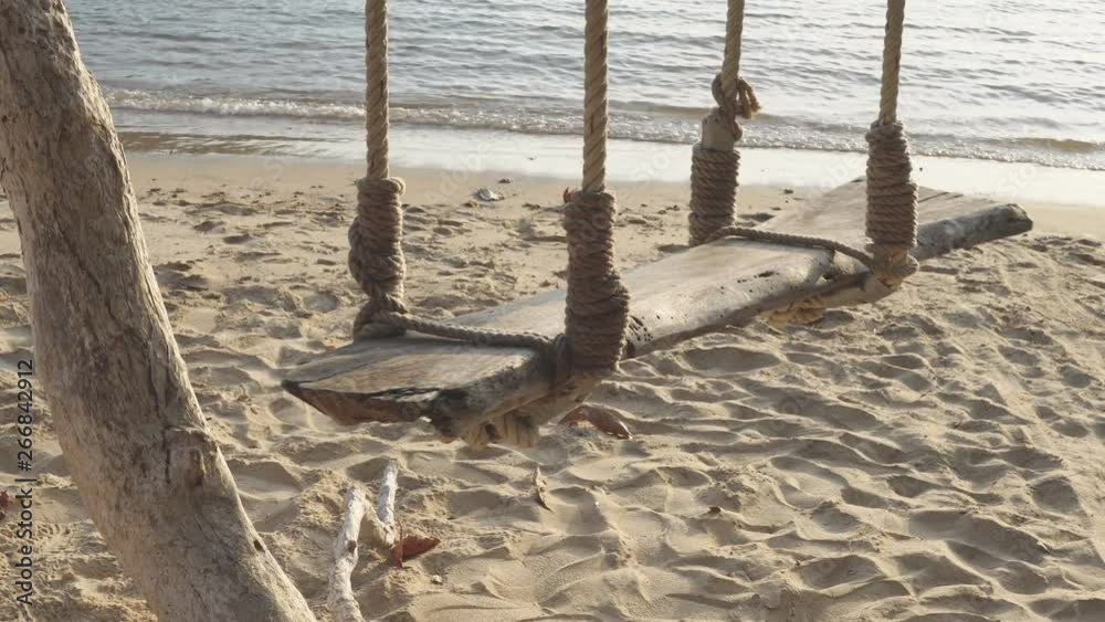 Sea wave on the beach and Wooden swing hang under a tree