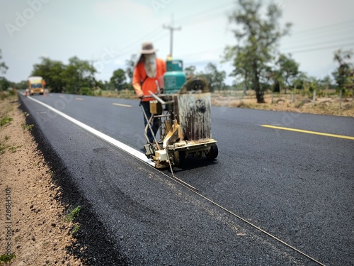 Technicians are working on traffic lines on the asphalt surface.