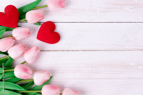 Women's day, Mother's day, Valentine's day concept Pink tulips bouquet with red heart on white wooden background, top view and copy space for card and advertiser.