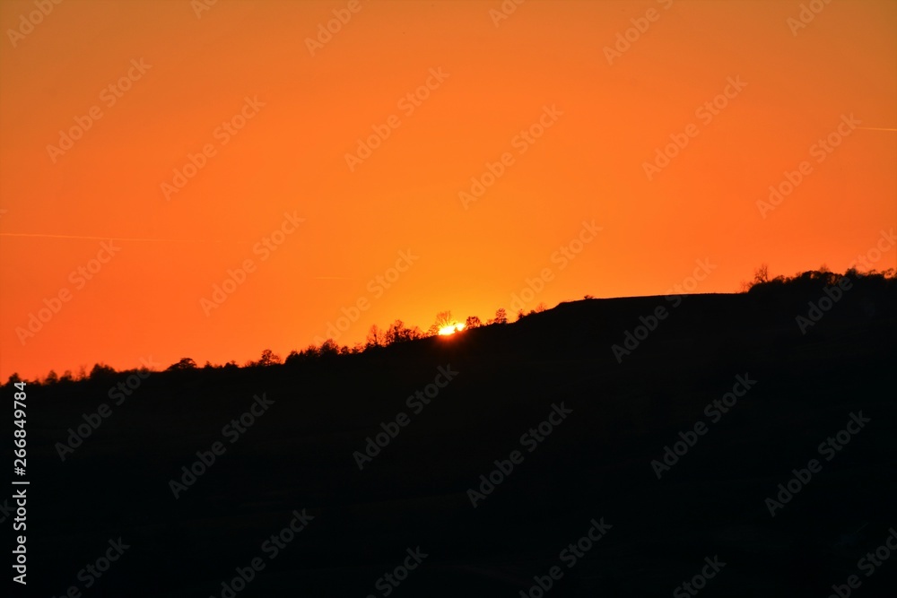 The sun sets down a hill