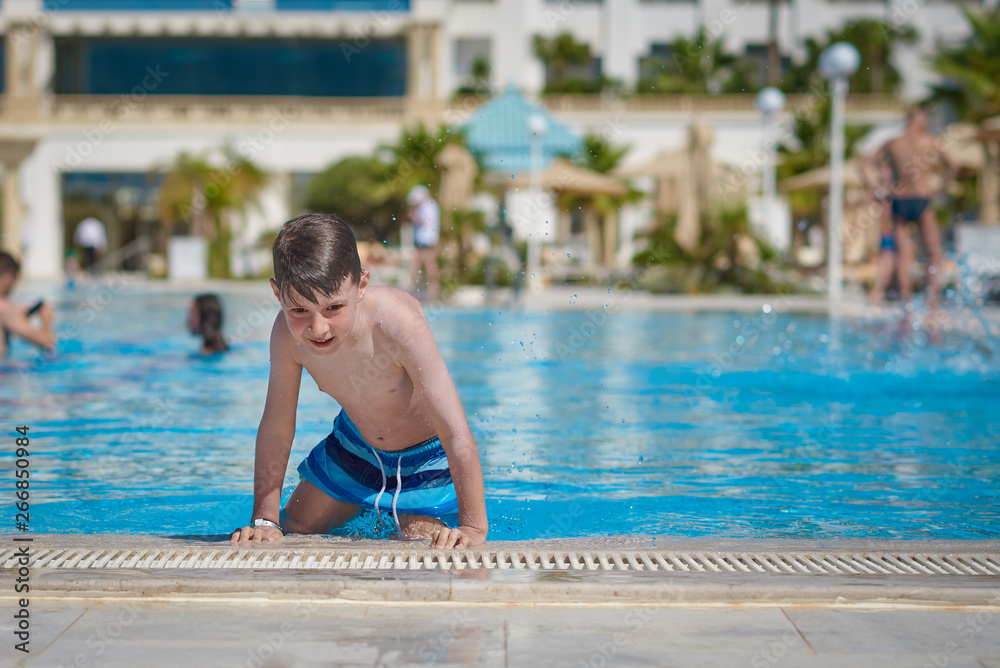 Portrait of happy cheerful European boy on side of swimming pool.