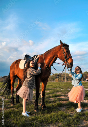 Two sisters and horse outdoors.