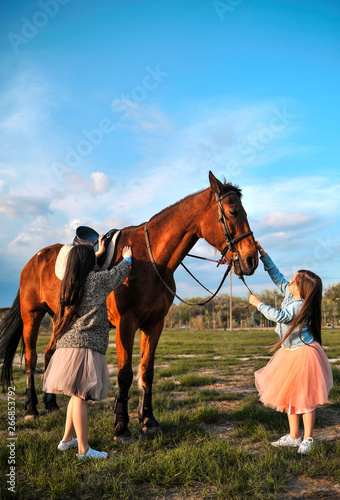 Two sisters and horse outdoors.