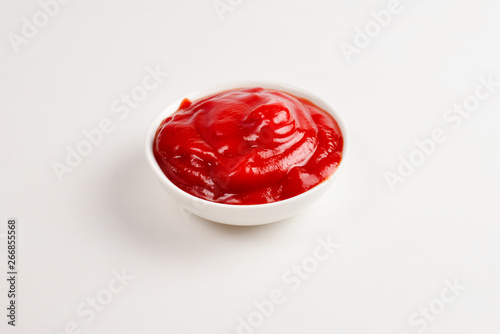 Ketchup in white plate on white background.