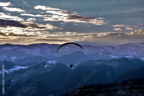 with the paraglider above the mountains in the evening