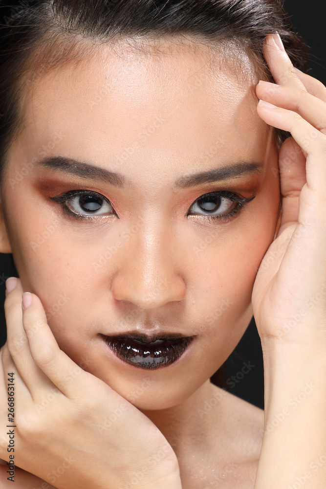 Young beautiful Asian woman makeup dark background 