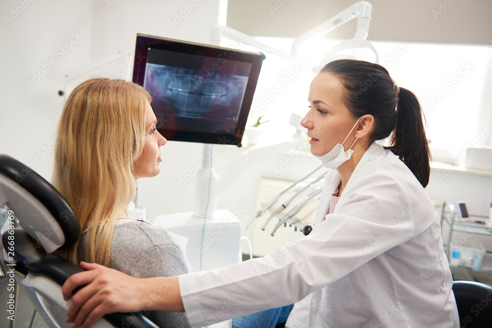Dentist talking to young woman during dental checkup Dentist talking to young woman during dental checkup