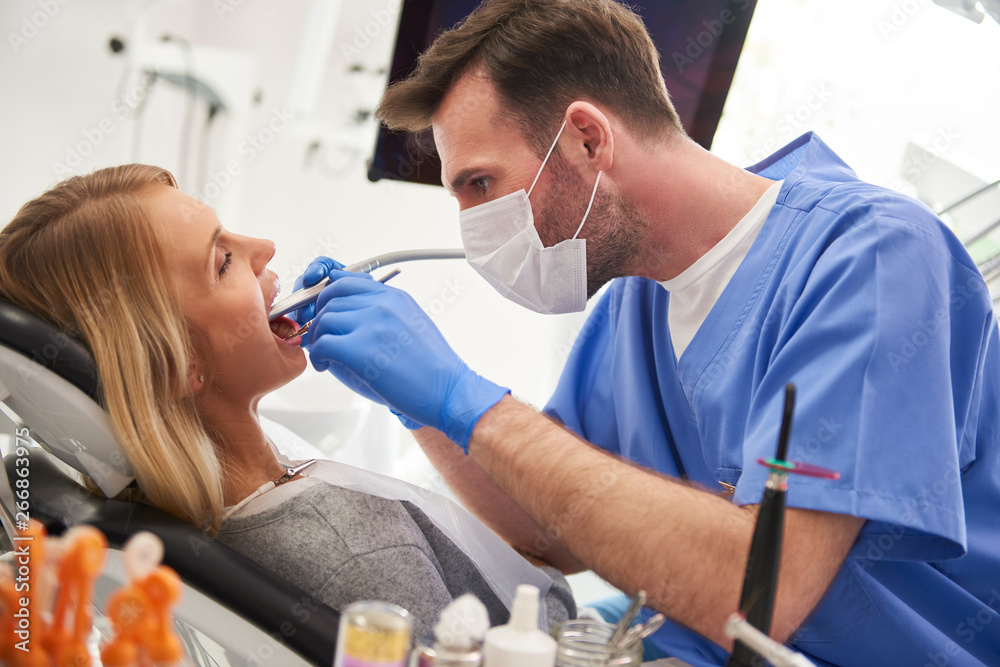 Fototapeta premium Focused stomatologist using dental drill and dental mirror