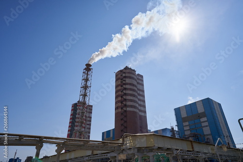 Large smoking chimney at a chemical fertilizer plant. Plant for the production of fertilizers against the blue sky