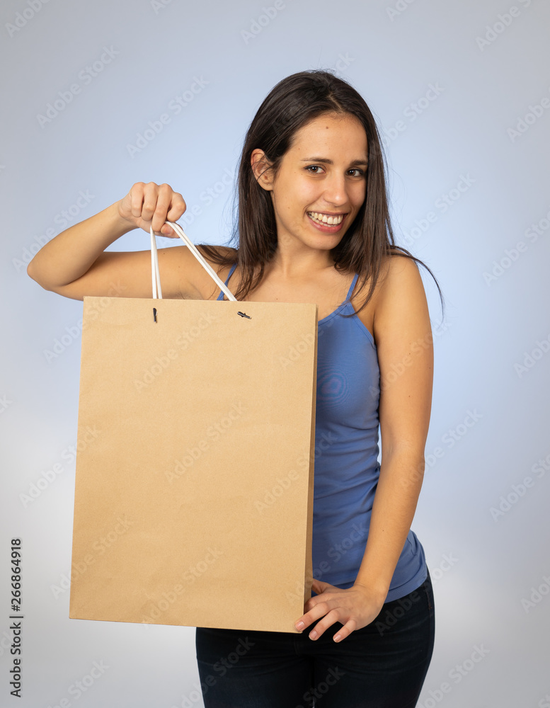 Beautiful young latin woman holding paper shopping bag with copy space Beautiful young latin woman holding paper shopping bag with copy space