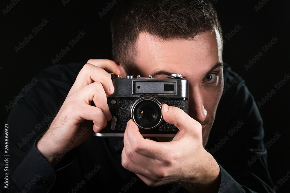 Man photographer holding a retro photo camera. Shooting process. Photographer looks at viewfinder. Man photographer holding a retro photo camera. Shooting process. Photographer looks at viewfinder.