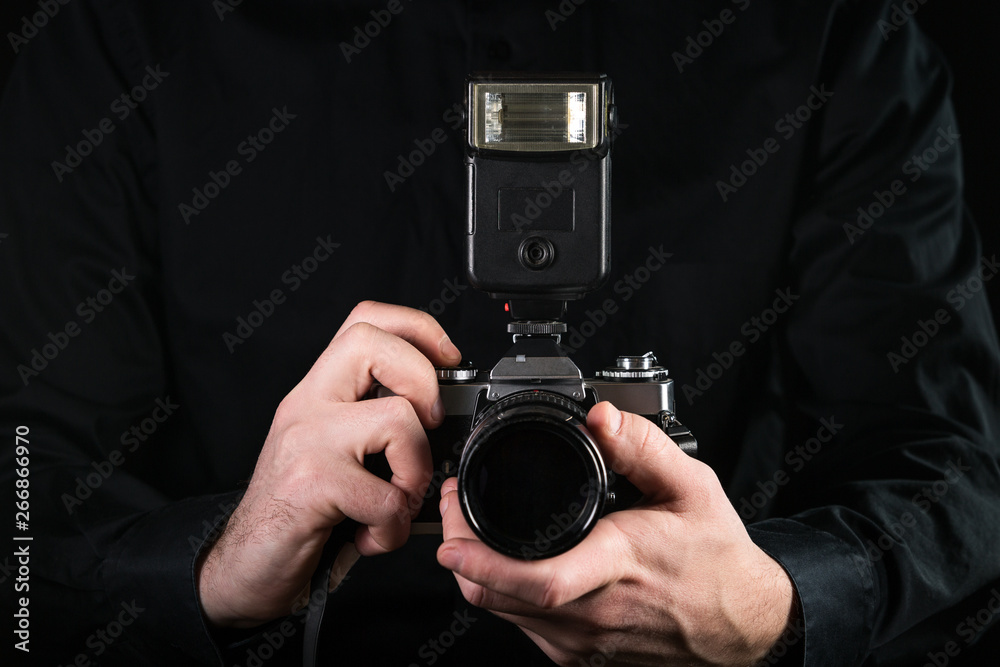Man photographer holding a camera. Shooting process. Retro 35mm film photo camera on black background.