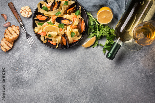 Mussels, bread toasts and white wine on stone table. Top view with copy space