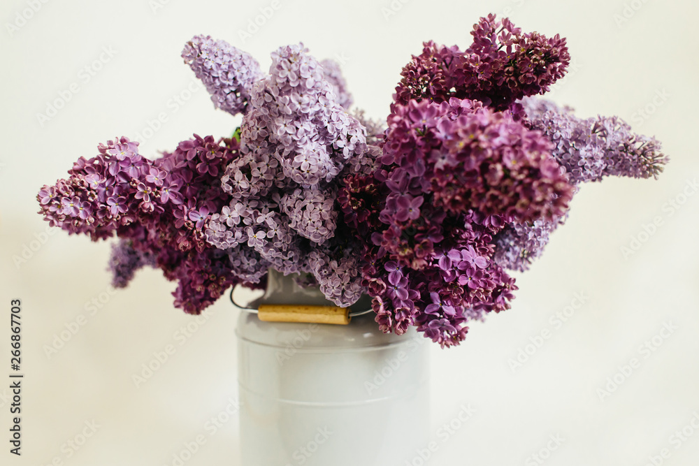 Obraz premium Purple bouquet of lilac flowers in a stylish vase on a white background