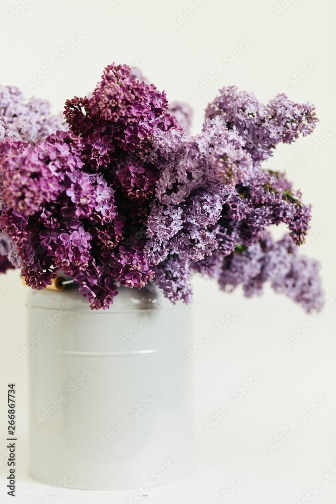 Obraz premium Purple bouquet of lilac flowers in a stylish vase on a white background