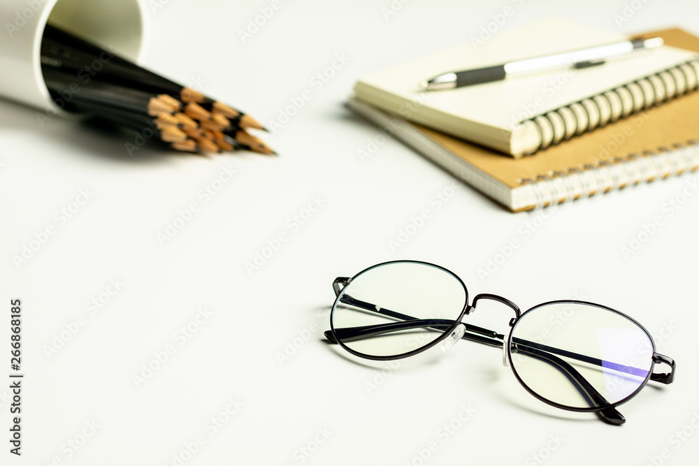white office desk with a glasses, pencil and a blank notebook. white office desk with a glasses, pencil and a blank notebook.