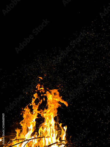  bright wild sparks of a burning campfire jumping on a black background at night