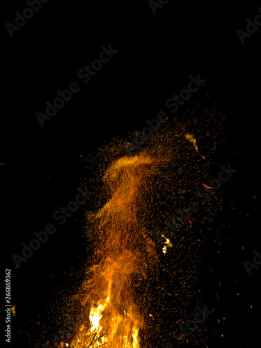 bright wild sparks of a burning campfire jumping on a black background at night
