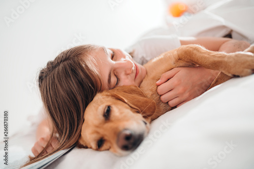 Girl embracing dog on the bed