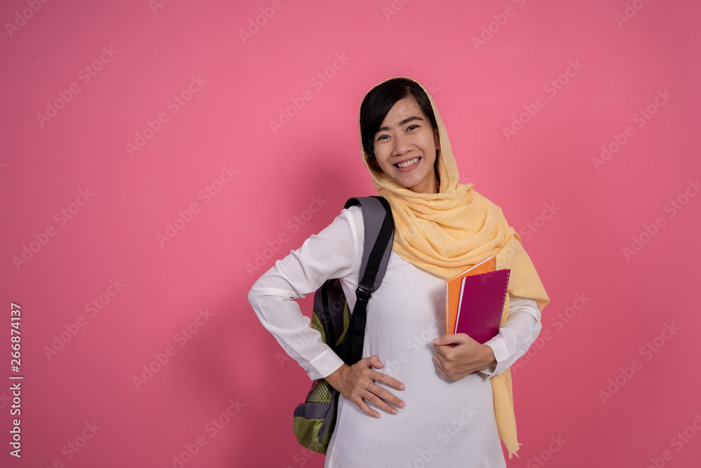 asian muslim woman wearing veil with book. muslim student on pink background asian muslim woman wearing veil with book. muslim student on pink background