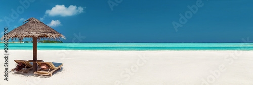 romantic getaway concept - tropical beach with two sunbeds under palapa and heart shaped cloud in maldives photo