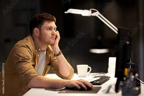 business, overwork, deadline and people concept - tired or bored man working late at night office photo