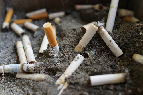 Many dirty cigarette butts on sand closeup