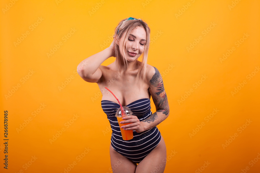 Charming caucasian woman in blue swimming suit and swimming glasses keeping her eyes closed over yellow background Charming caucasian woman in blue swimming suit and swimming glasses keeping her eyes closed over yellow background