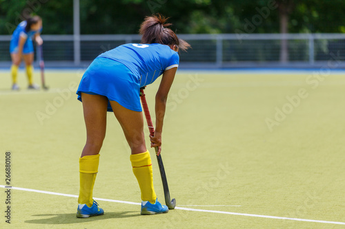 Young female field hockey player with stick on the pitch