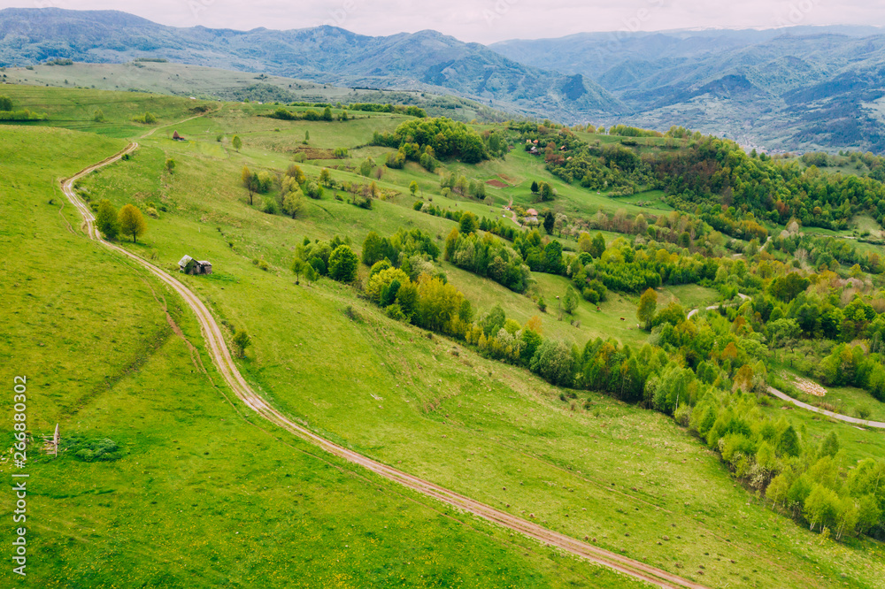 Drone view of green meadows, small houses and roads in Transylvania, Romania. Drone view of green meadows, small houses and roads in Transylvania, Romania.