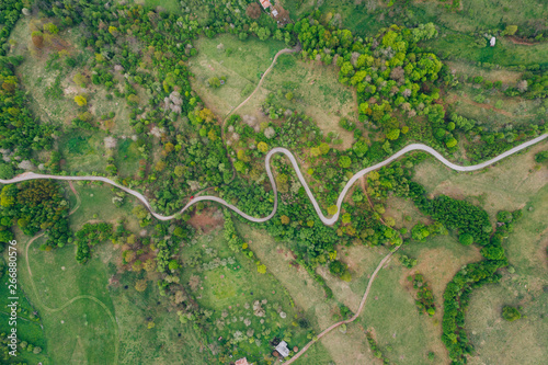 Drone view of green meadows, small houses and roads in Transylvania, Romania.