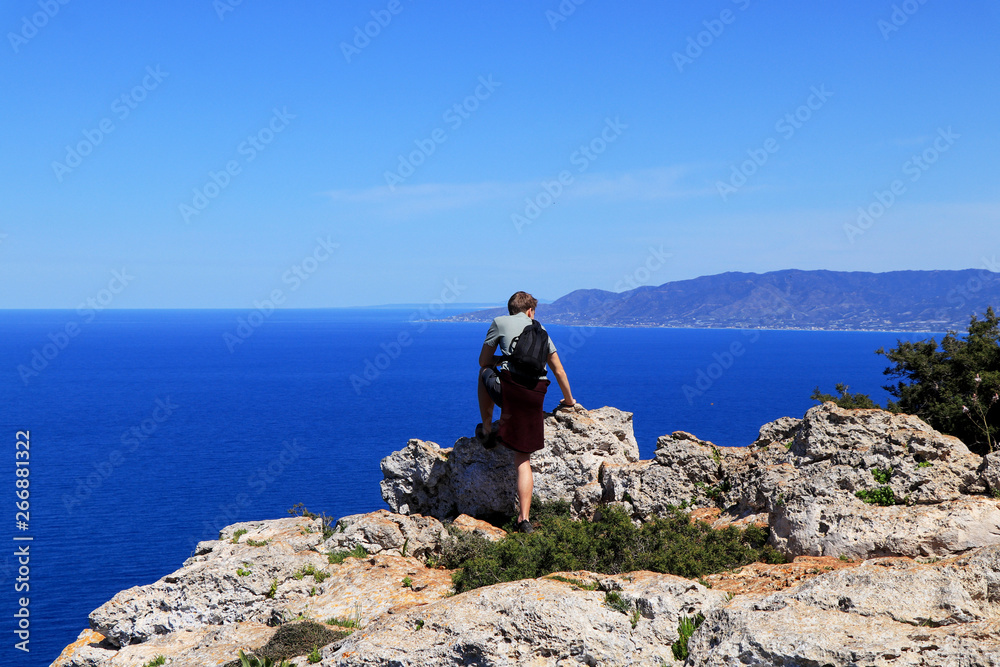 Athlete is enjoying the view on the peak of Akamas hill in Cyprus. He is feast one's eyes on mediterranean sea with mountain in background. Young boy relax on the mountain and looks on cypriot nature