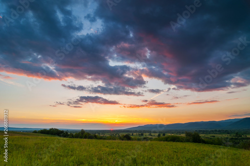 Colorful and dramatic sunset over a green field