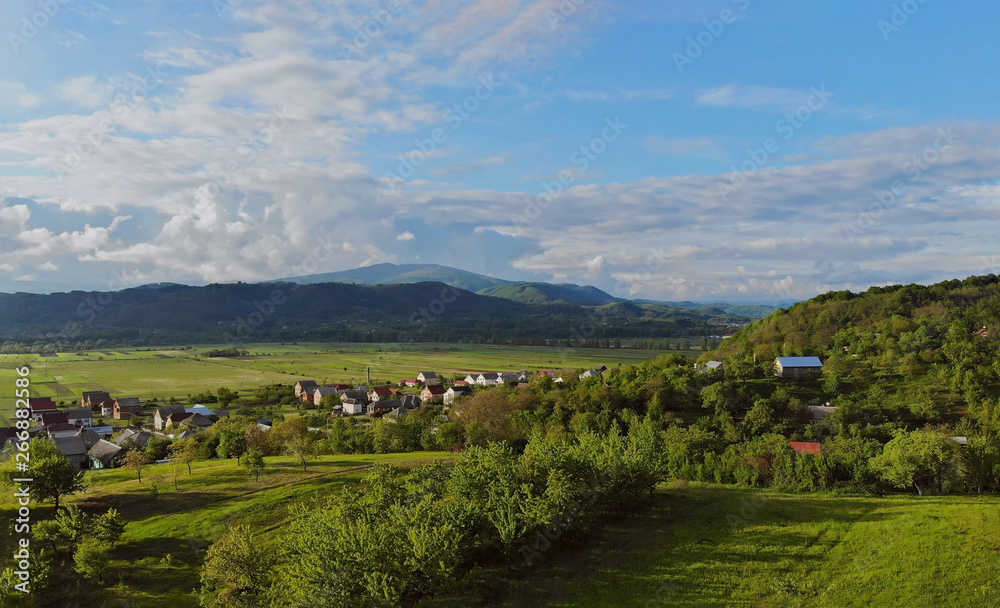 Aerial view of small village surrounded by mountains a sunny summer day and blue sky Karpaty Ukraine