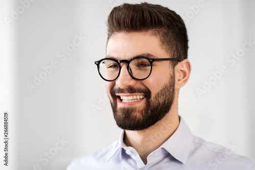 business people, emotion and facial expression concept - portrait of happy smiling bearded businessman in glasses