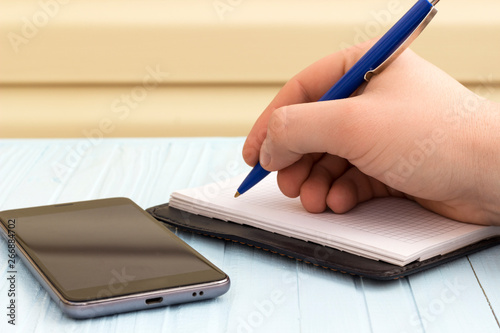 man taking notes in a notebook from a phone