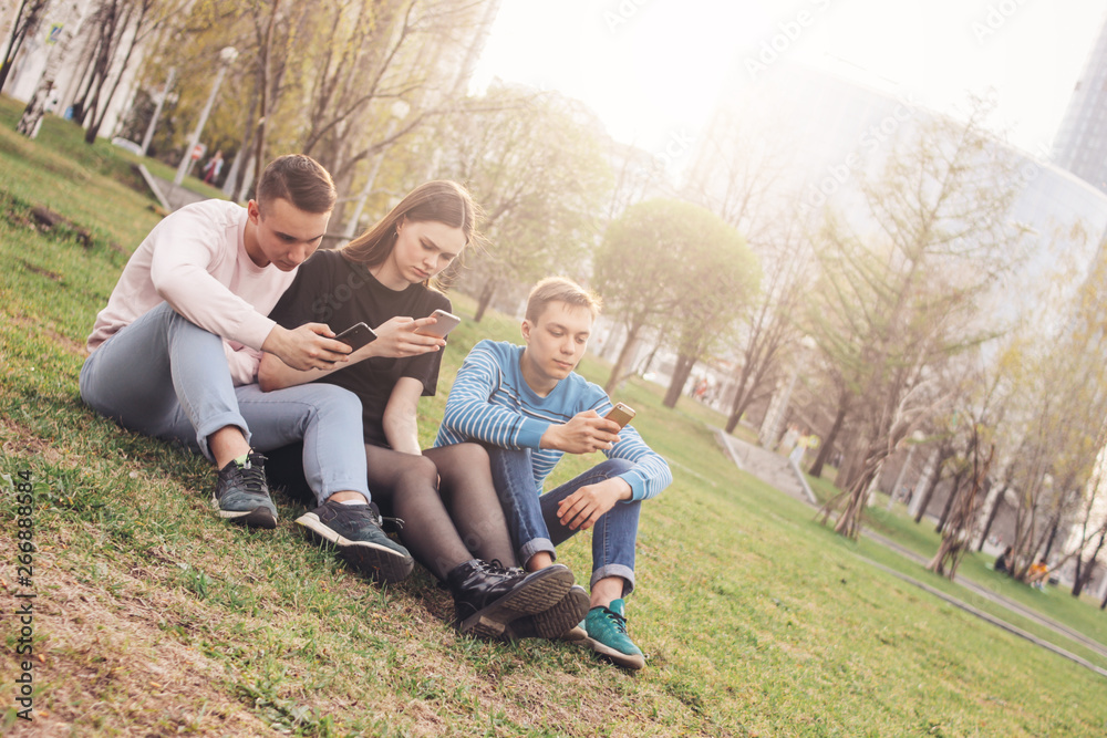 The group of young friends teenagers using mobile at the city street