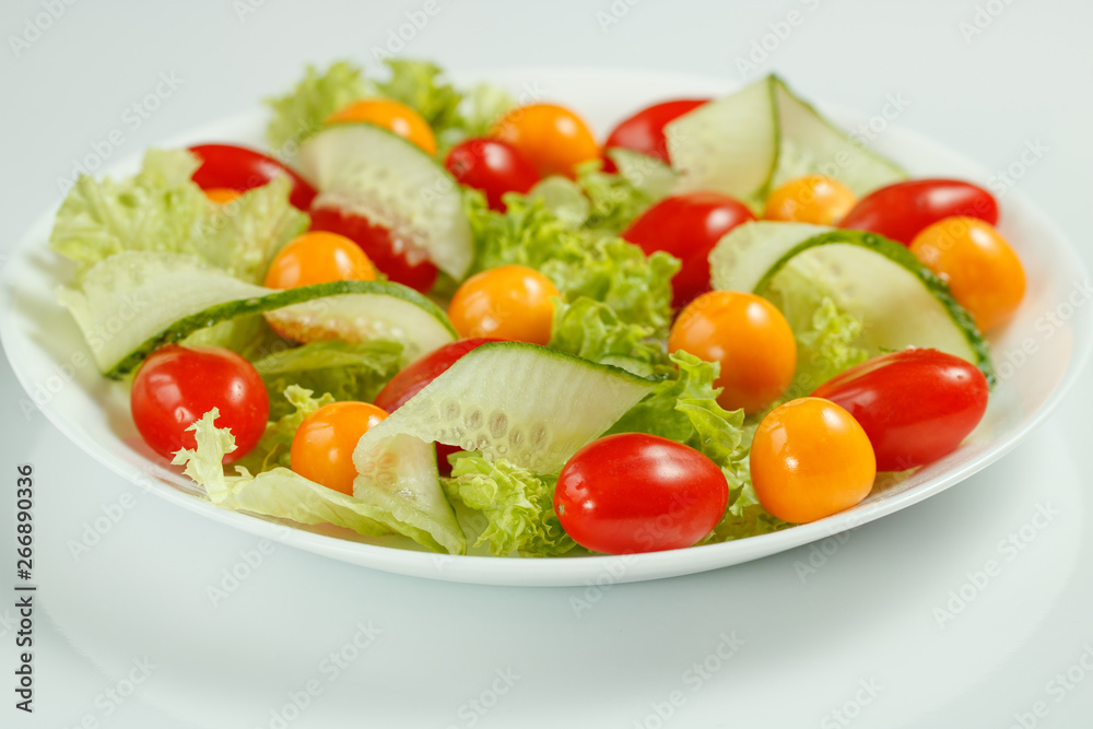 healthy vegan lunch with green salad and red yellow tomatoes on a white background