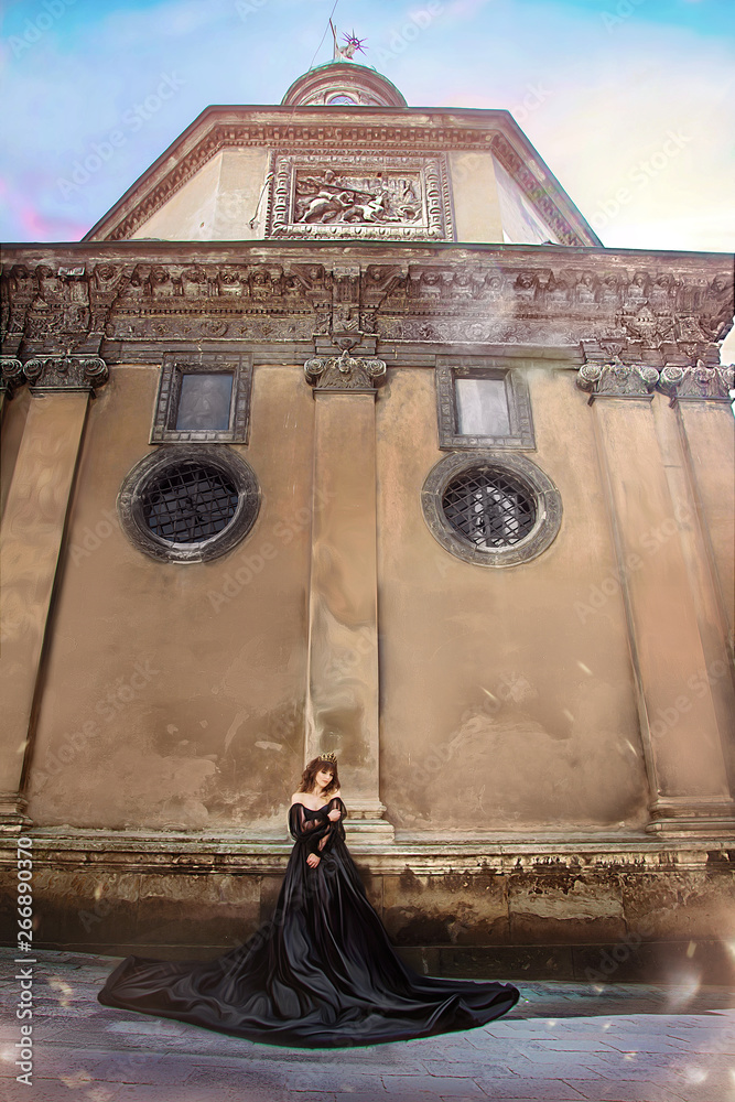 Princess in magnificent black dress and tiara, on background of the old cathedral in Lviv. Ukraine