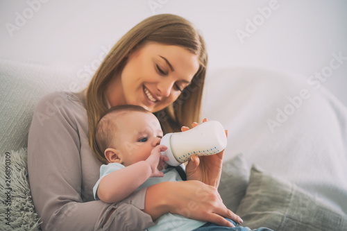 Cuadro en lienzo Happy mother is feeding her baby boy at home.