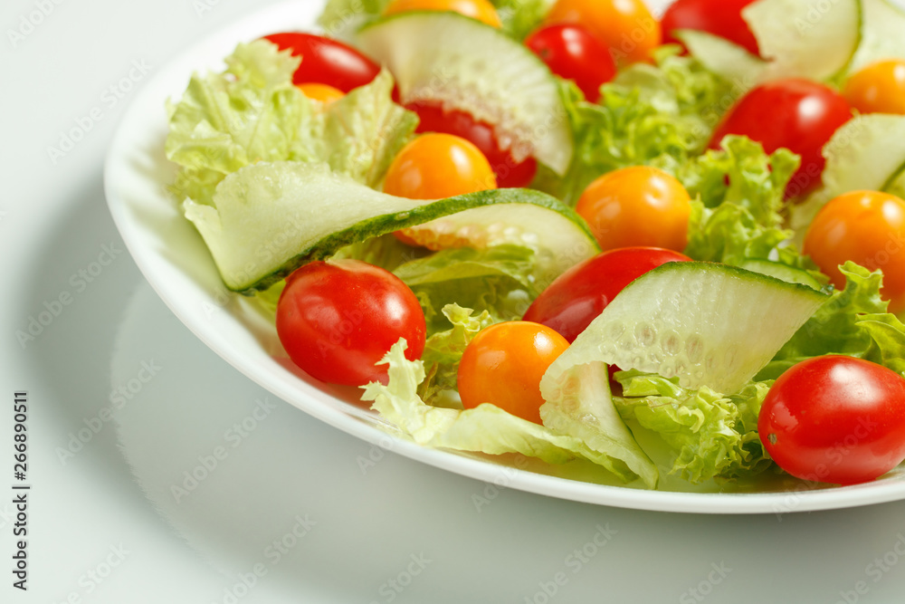 healthy vegan lunch with green salad and red yellow tomatoes on a white background