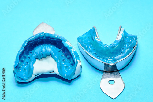 Two dental impressions on a blue background. Dental molds from the upper and lower jaws of silicone material. The imprint of the tooth row of high precision. photo