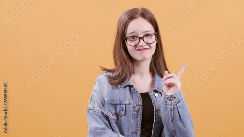Beautiful teenage girl dissaproves and nagates something. Portrait of a very young female over a yellow background. photo