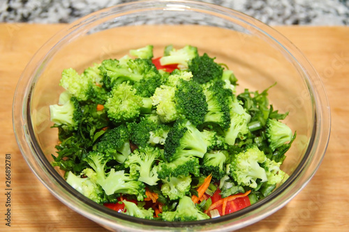 green broccoli salad in a glass plate on a wooden board background