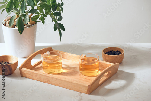 Hot tea is in the glass. Placed on a wooden tray. photo