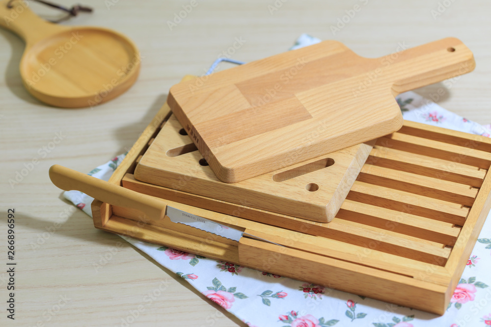 Kitchenware collecttion set, Vintage cutting wood board and tray with bread knife lie on cloth napkin and wooden table background