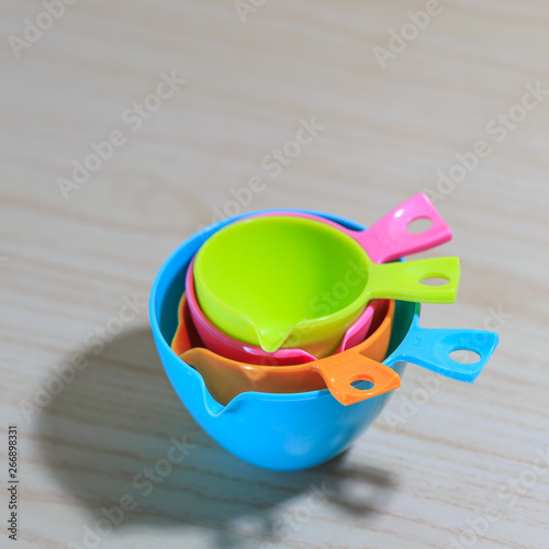 Nested colorful measuring cups isolated on white wooden table background