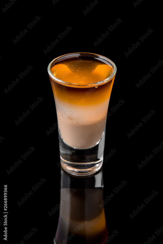 Alcoholic cocktails B-52 in shot glasses (shooters).  Cool drink from strong vodka, whiskey, coffee liqueur, baileys. Isolated on black background. Cocktail card for a bar or restaurant.