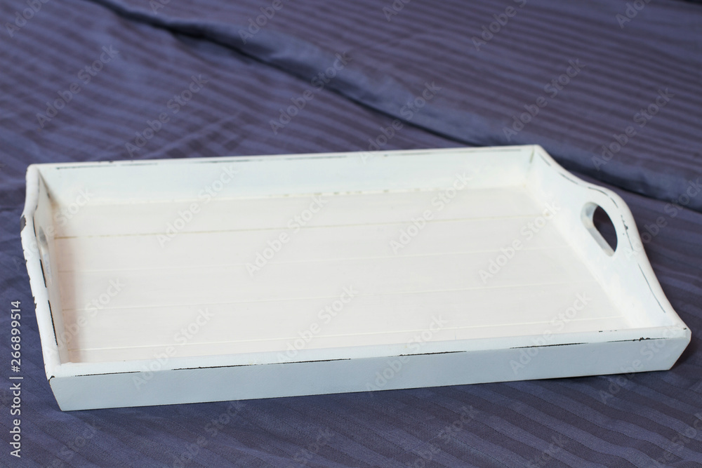 Hotel food offerings, quick service concept. Empty white tray with copy space at bedroom bed. Top view, place for meal. Freshly prepared food offering options. Takeaway delivery. Selective focus
