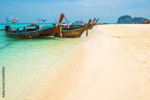 Landscape of beautiful blue sea and white sand beach with moored traditional boats at tropical island 